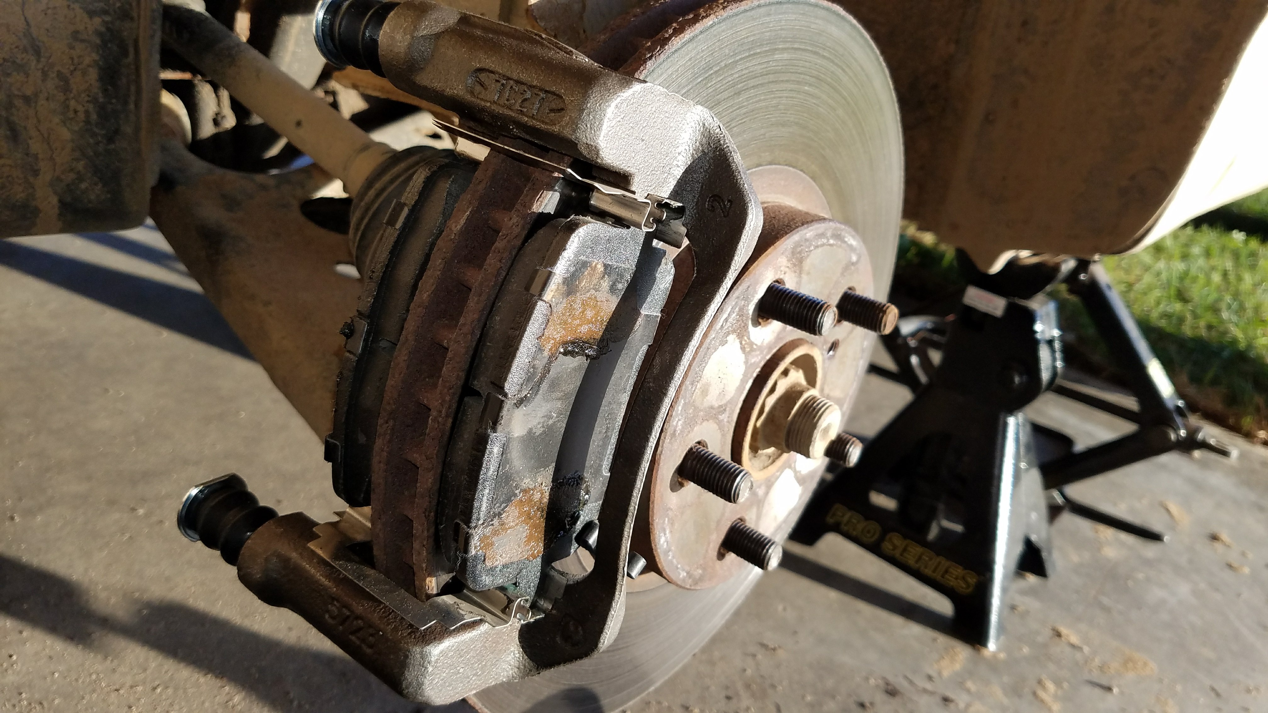 Caliper removed from brake pads, with new caliper bracket installed.