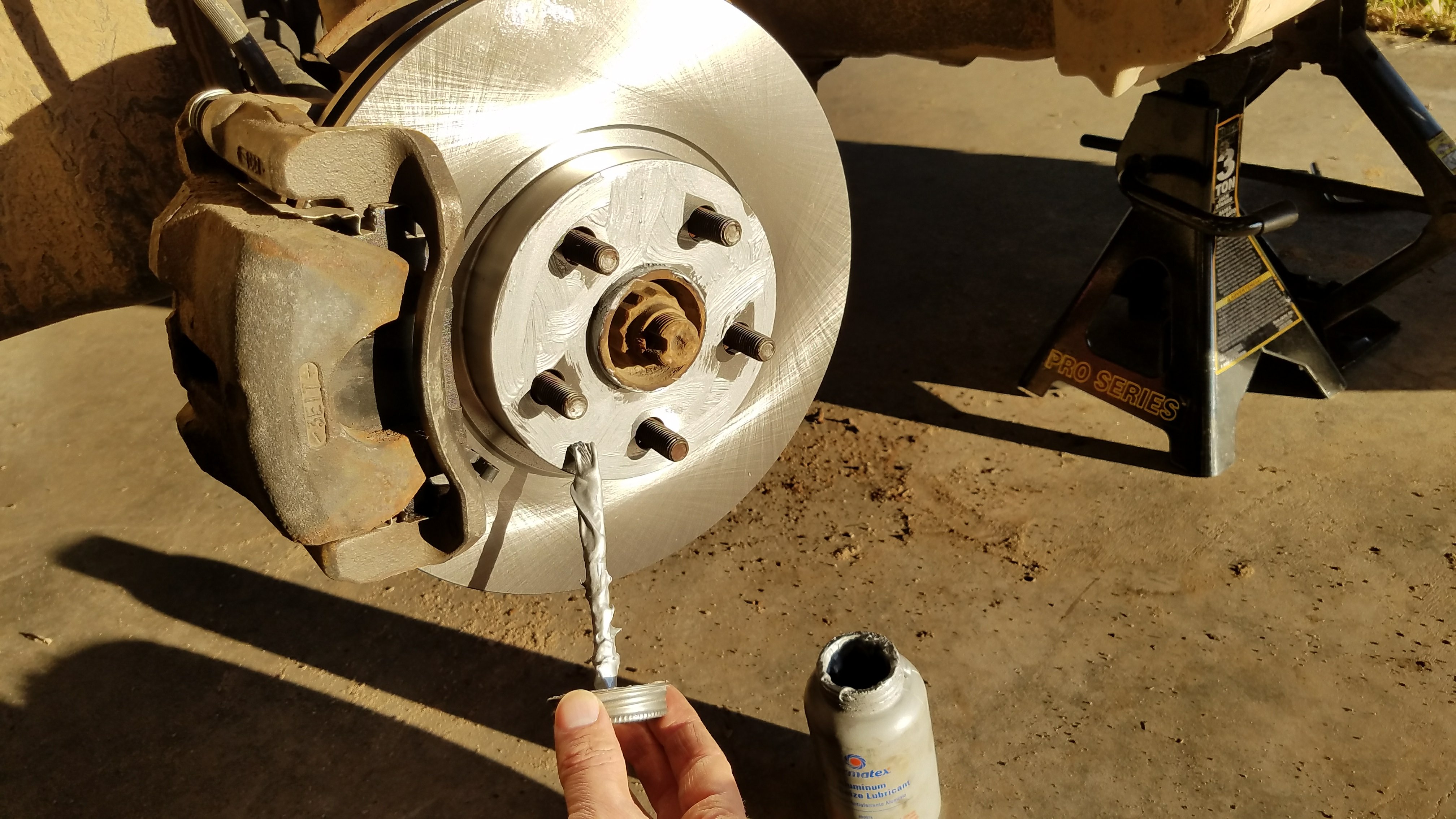 Spreading anti-seize onto the face of the brake rotor.