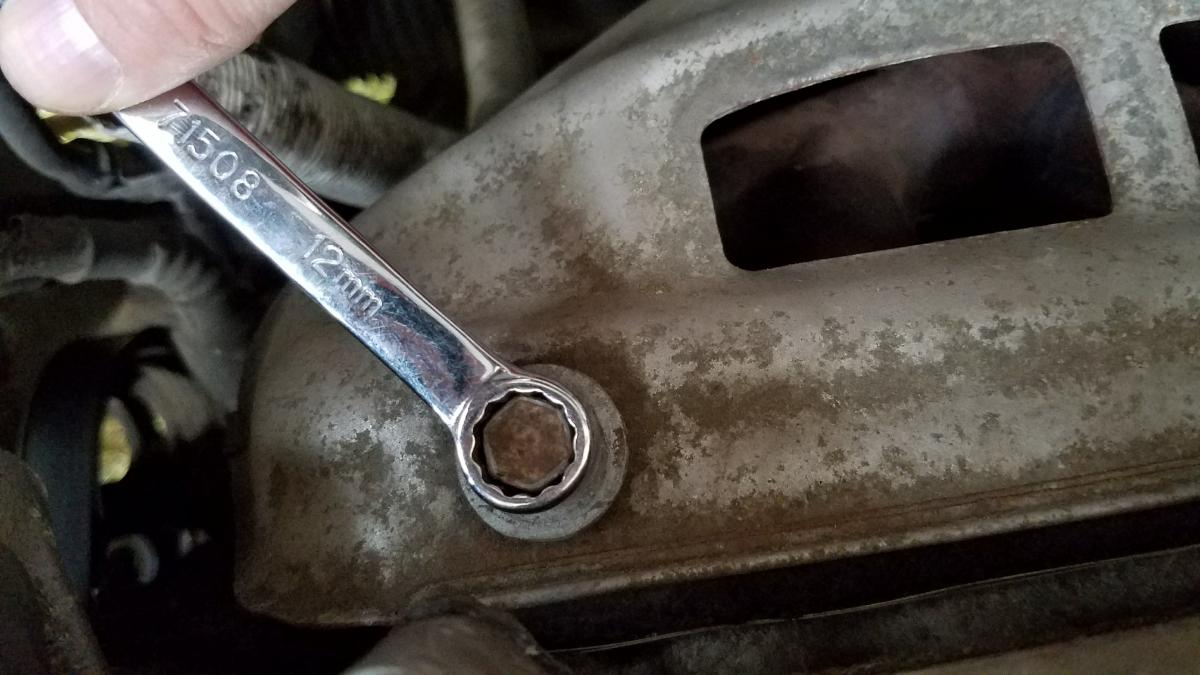 Removing the baffle with a 12mm wrench to access the 02 sensor on a toyota corolla