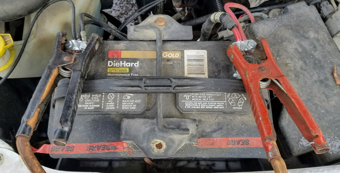 A car battery with jumper cables attached.