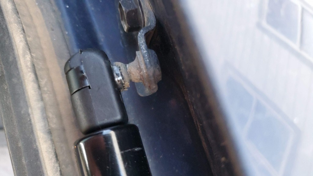 The new tailgate strut lined up, but not yet pressed onto the fitment knob.