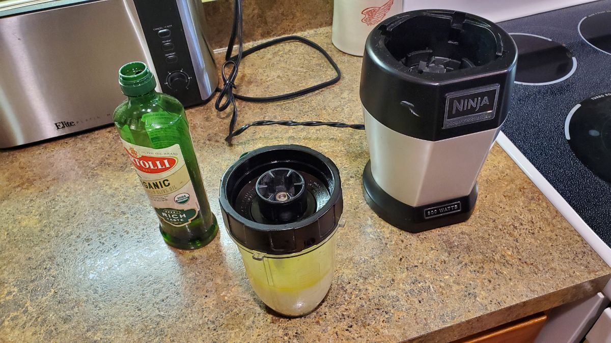 Ninja blender with olive oil and water mixture inside.